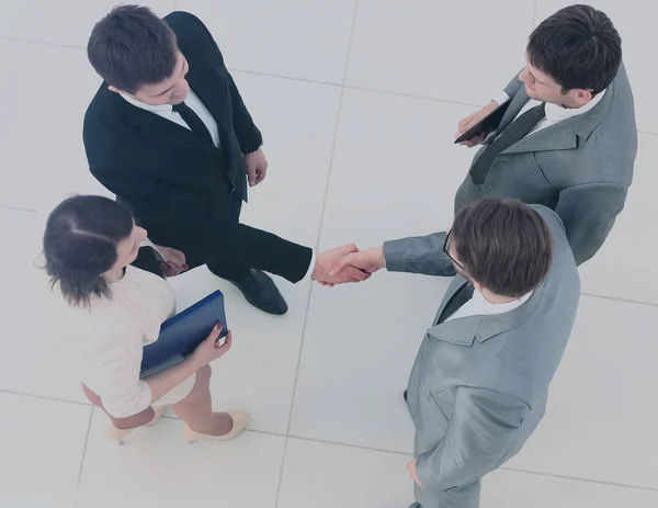 Reunión de negocios. Vista superior de cuatro personas en ropa formal de pie uno cerca del otro, mientras que dos de ellos apretón de manos —  Fotos de Stock