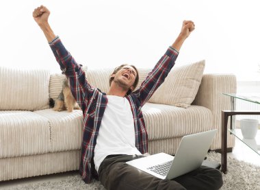 mutlu genç adam köpeğiyle oturma odasında exults