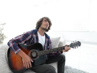 modern adam kanepede oturan gitar çalmak. bir yaşam tarzı kavramı