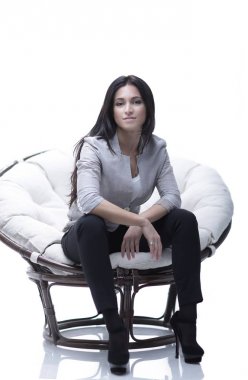 Genç kadın bir yuvarlak rahat yumuşak büyük sandalyede oturuyor.