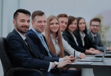 Kendine güvenen işadamı meslektaşları arasında kamera bakıyor