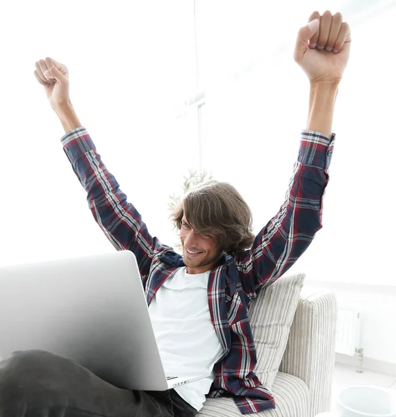 Πολύ χαρούμενος νεαρός άνδρας που εργάζεται με το laptop στο σπίτι. — Φωτογραφία Αρχείου