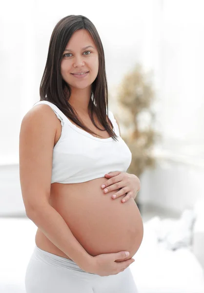 Portrait of young pregnant woman on a light background. — Stock Photo, Image