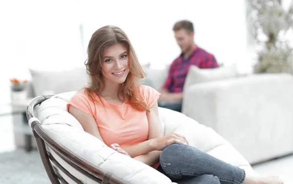 Sonriente joven sentada en una silla grande y cómoda — Foto de Stock