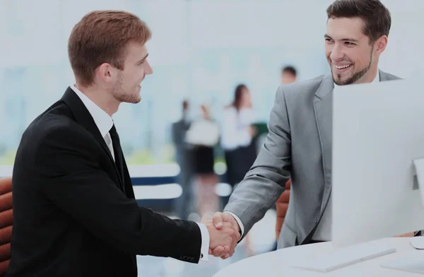 Due giovani uomini felici che si stringono la mano mentre si siedono in ufficio — Foto Stock