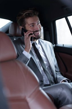 İş adamı arkada telefonla konuşuyor.
