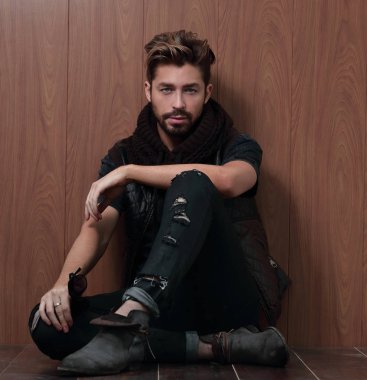 Sıradan giyinmiş sakallı bir adam oturur.