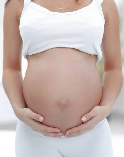 Close-up van een zwangere vrouw die haar handen op haar buik te zetten. — Stockfoto