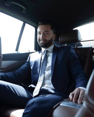 bir arabanın arka koltuğunda oturan işadamı