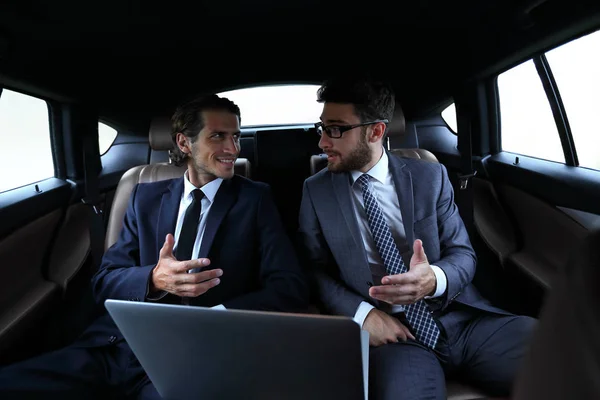 Two businessman talking while sitting in the car — Stock Photo, Image