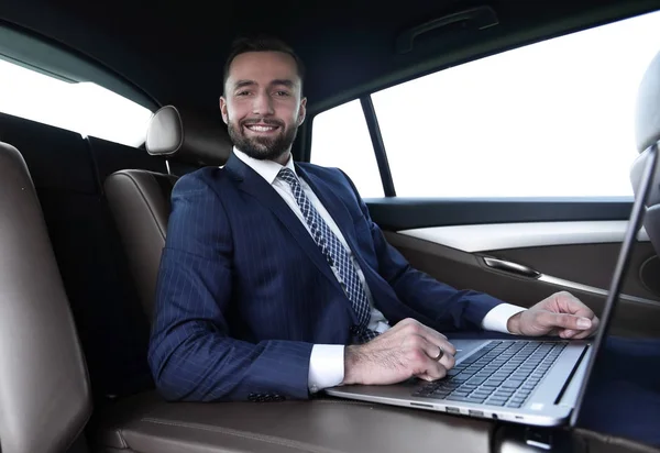 Hombre exitoso que trabaja con el ordenador portátil sentado en el coche —  Fotos de Stock