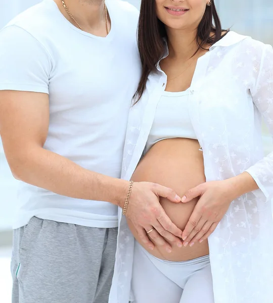 Mari et femme enceinte avec les mains pliées en forme de coeur sur son ventre — Photo