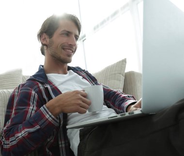 genç adam kanepede yakın katta oturan çay içiyor.