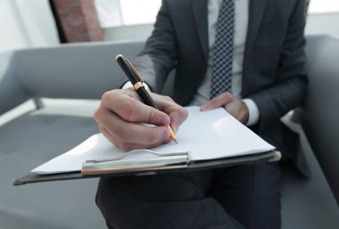 İşadamı bir sözleşme imzalar. Elinde kalem tutan.