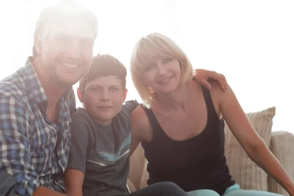 Los padres y su hijo se sientan acurrucados en la sala de estar y sonriendo —  Fotos de Stock