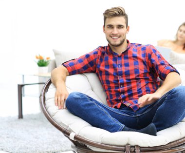 arka plan bulanık bir büyük yuvarlak sandalyede oturan modern genç adam