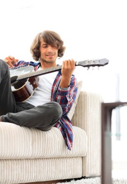 Yakışıklı adam evde kanepede gitar çalmaya