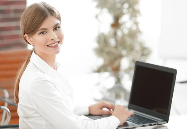 Joven mujer de negocios sentada en su escritorio en una oficina, trabajando en una computadora portátil — Foto de Stock