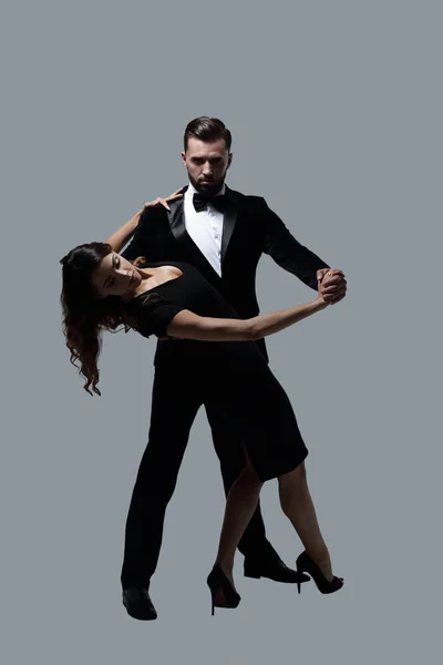 Портрет молодой пары, танцующей на сером фоне — стоковое фото