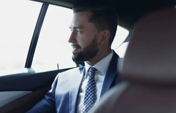 Smiling business man sitting in the back seat of a car