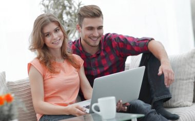 Genç çift çalisarak koltukta oturan laptop