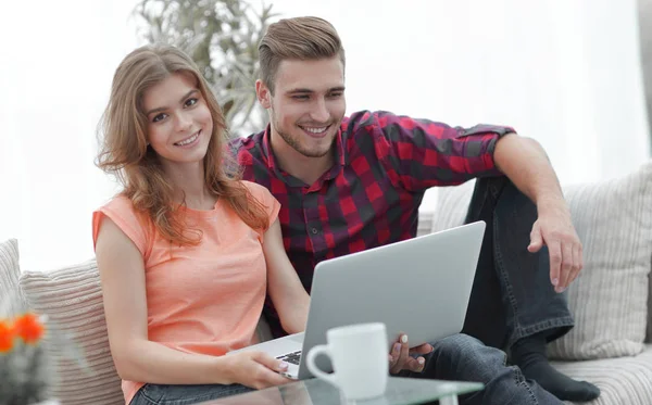 Pareja joven .working en el ordenador portátil sentado en el sofá —  Fotos de Stock