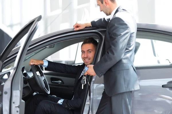 Uomo d'affari di successo, ricevendo le chiavi dell'auto dal venditore nello showroom — Foto Stock