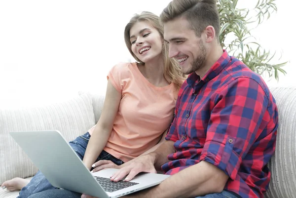 Усміхнена молода пара з ноутбуком сидить на дивані — стокове фото