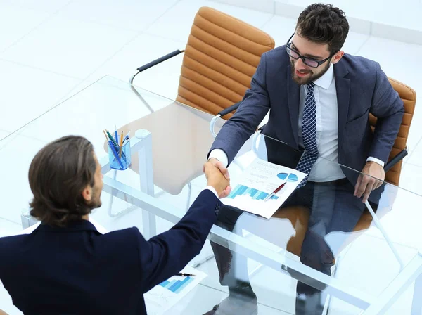 Uścisk dłoni z partnerami biznesowymi, siedząc przy biurku — Zdjęcie stockowe