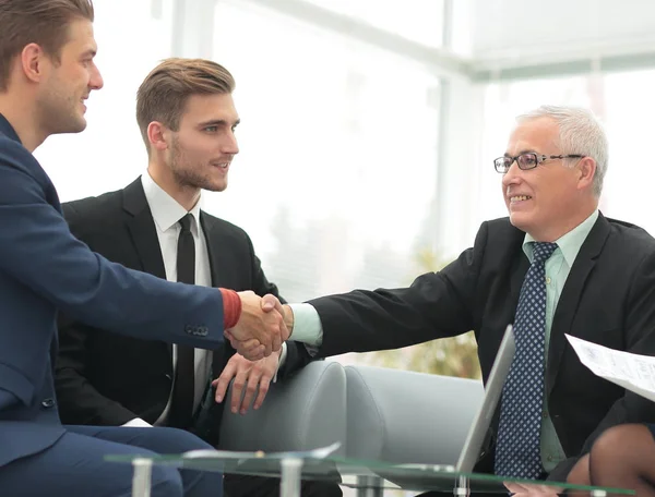 Socios concluyendo trato y estrechando la mano en presencia de los miembros del equipo — Foto de Stock