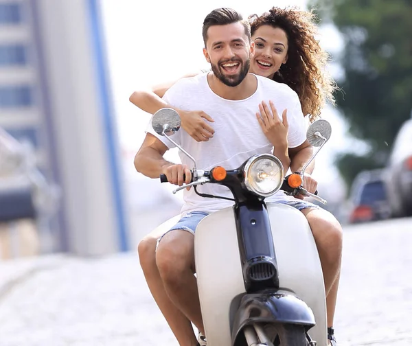 Happy young couple riding a scooter in the city on a sunny day — Stock Photo, Image