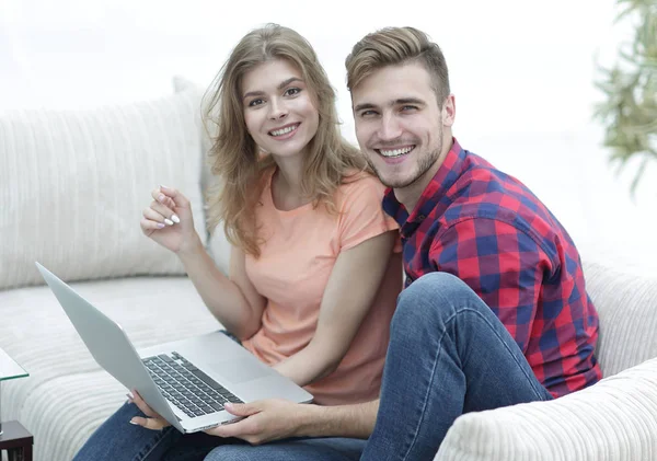 Par studenter med en bärbar dator sitter på soffan — Stockfoto