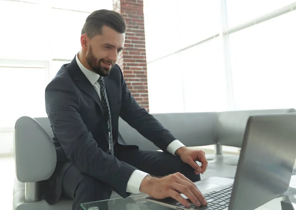 Hombre de negocios trabajando en portátil sentado en el vestíbulo de la oficina — Foto de Stock