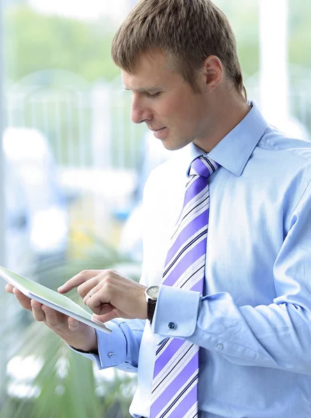 Beau jeune homme en chemise bleue à l'aide d'une tablette — Photo