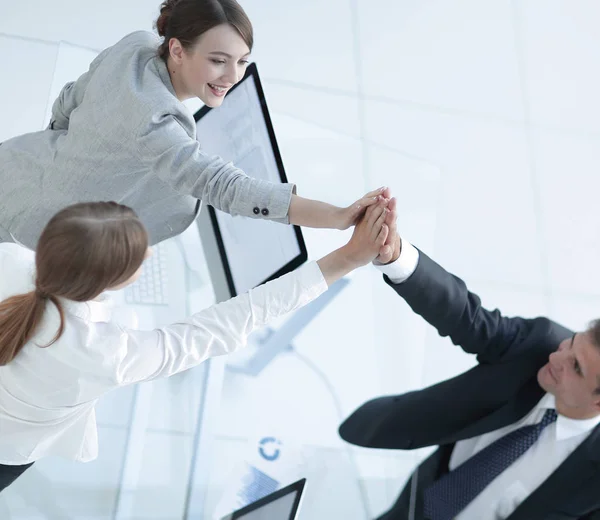 Vista a partir do topo. Membros da equipe de negócios dando uns aos outros um alto cinco acima da mesa . — Fotografia de Stock