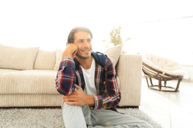 Samimi bir oturma odasındaki halının üzerinde oturan rüya gören bir adamın yakın çekimi.