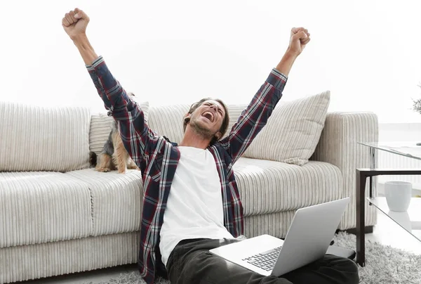 Feliz joven se regocija con su perro sentado en la sala de estar — Foto de Stock