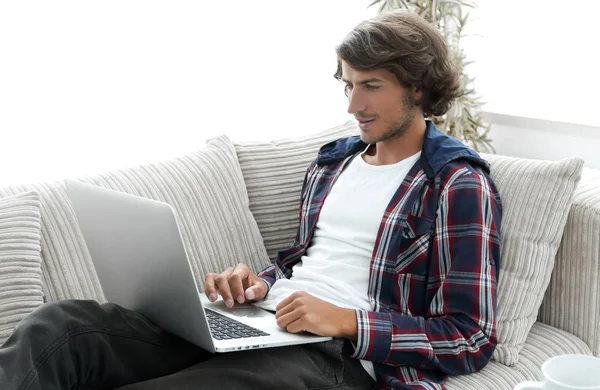 Νεαρός άνδρας που εργάζονται για το laptop που κάθεται στον καναπέ — Φωτογραφία Αρχείου