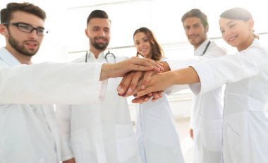 Doktorlar ve hemşireler tıbbi bir ekipte el ele tutuşuyorlar.