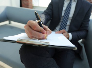 İşadamı bir sözleşme imzalar. Elinde kalem tutan.
