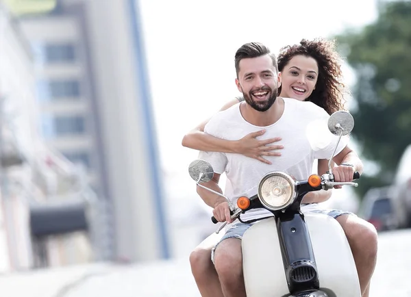 Happy young couple riding a scooter in the city on a sunny day — Stock Photo, Image