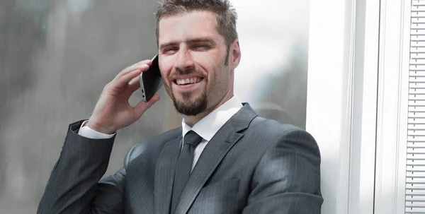 Empregado falando ao telefone, sentado no peitoril da janela — Fotografia de Stock