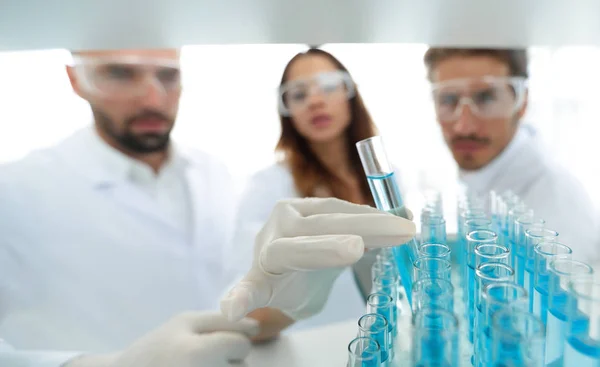 Imagen de fondo es un grupo de científicos que estudian el líquido en el tubo de vidrio . — Foto de Stock