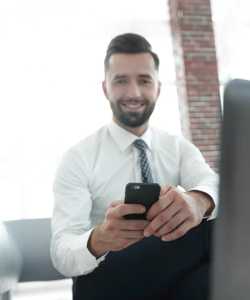 Affärsman håller en smartphone och tittar på kameran — Stockfoto