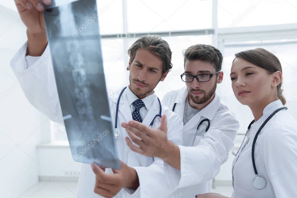 Three confident doctors examine an x-ray