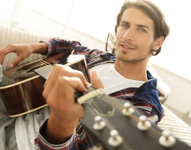 gitar oturma odasında kanepede oturan adam. bir yaşam tarzı kavramı