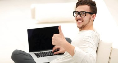 açık belgili tanımlık laptop önünde oturan ve gösterilen modern genç yukarı başparmak