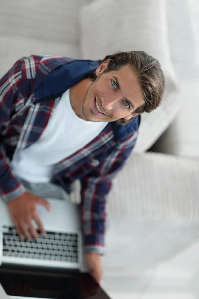 Un tânăr care lucrează la laptop și se uită la cameră. vedere de sus — Fotografie, imagine de stoc