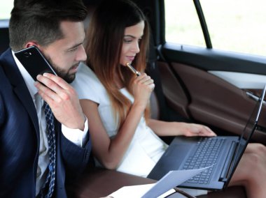 Genç iş adamları arabada birlikte çalışıyorlar.