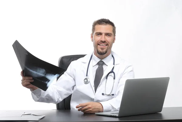 Médico examina um raio-x, sentado atrás de uma mesa — Fotografia de Stock